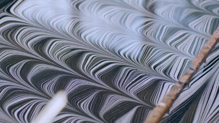 Close-up of detailed black and white striped patterns in a paper marbling tray.