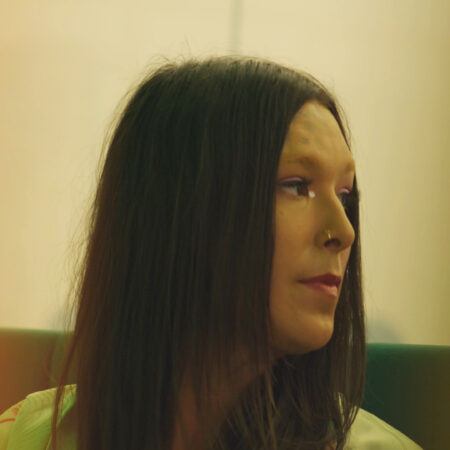 Jade Guanaro Kuriki-Olivo with long, dark hair looks to the side, wearing a nose ring.