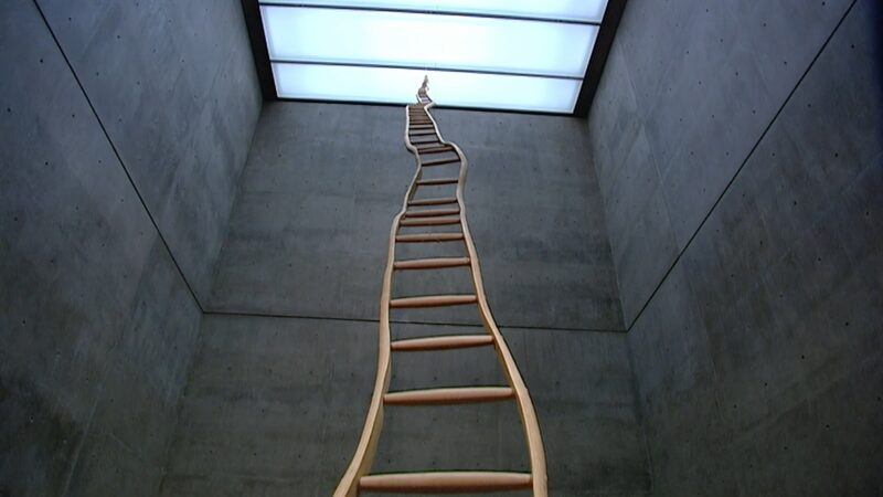 A person shapes hot molten glass with metal tools during the glassblowing process.